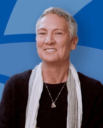 Smiling person with short gray hair against a blue background.