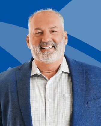 Smiling middle-aged man in a blue blazer and checkered shirt.