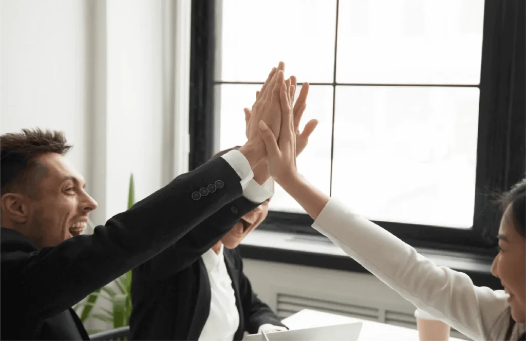 Two people in business attire exchanging a high-five in an office