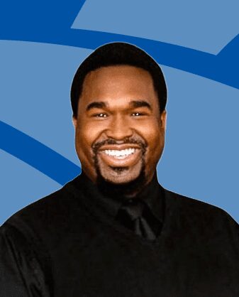 Smiling man in black shirt with blue background.