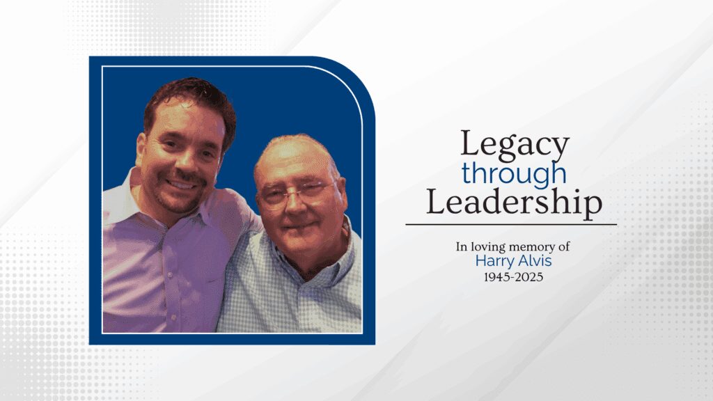 Smiling duo beside "Legacy through Leadership" memorial
