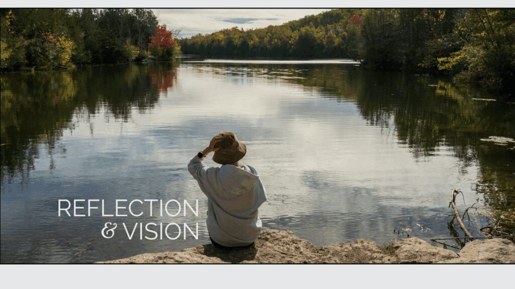 Person sitting by calm lake, reflecting.