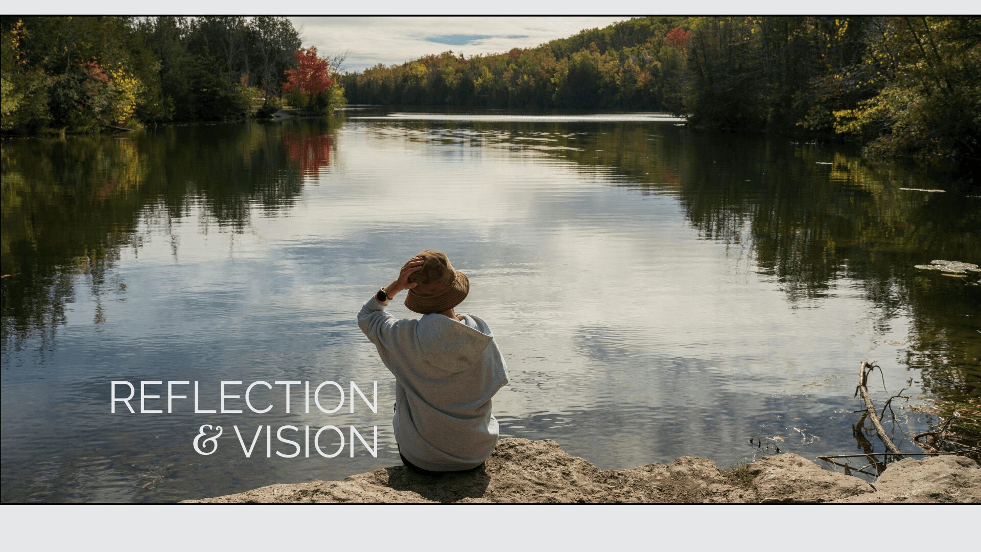 Person sitting by calm lake, reflecting.